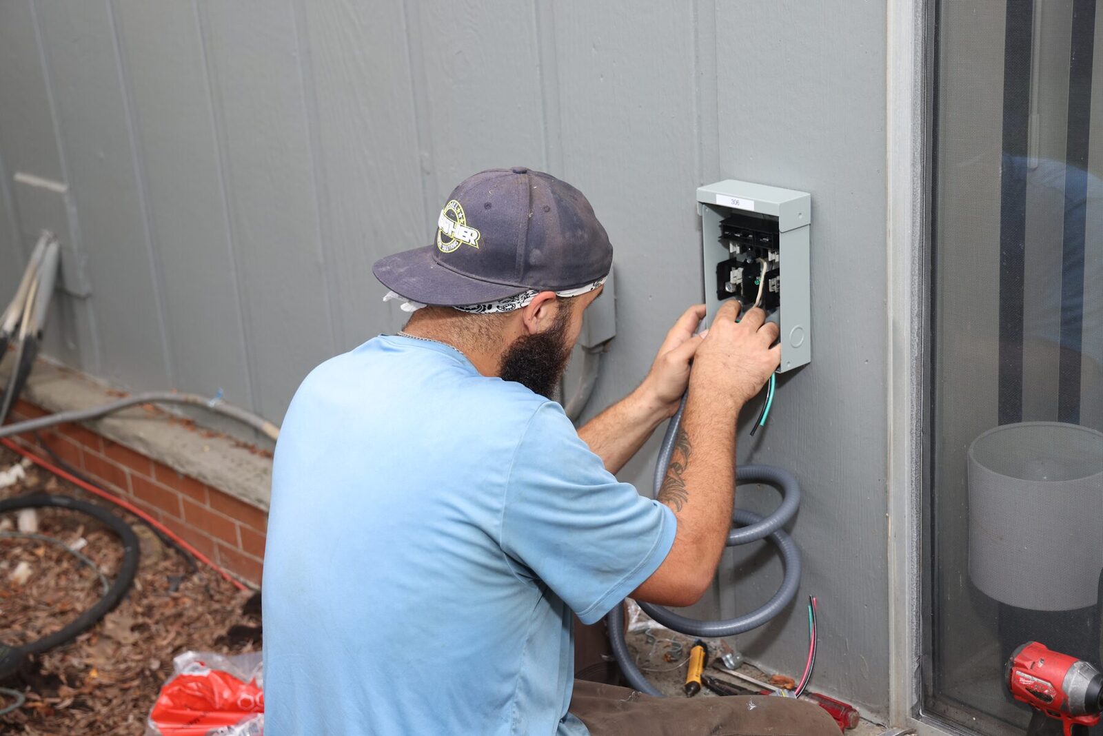 An All Weather Comfort Solutions technician repairing an outdoor AC disconnect