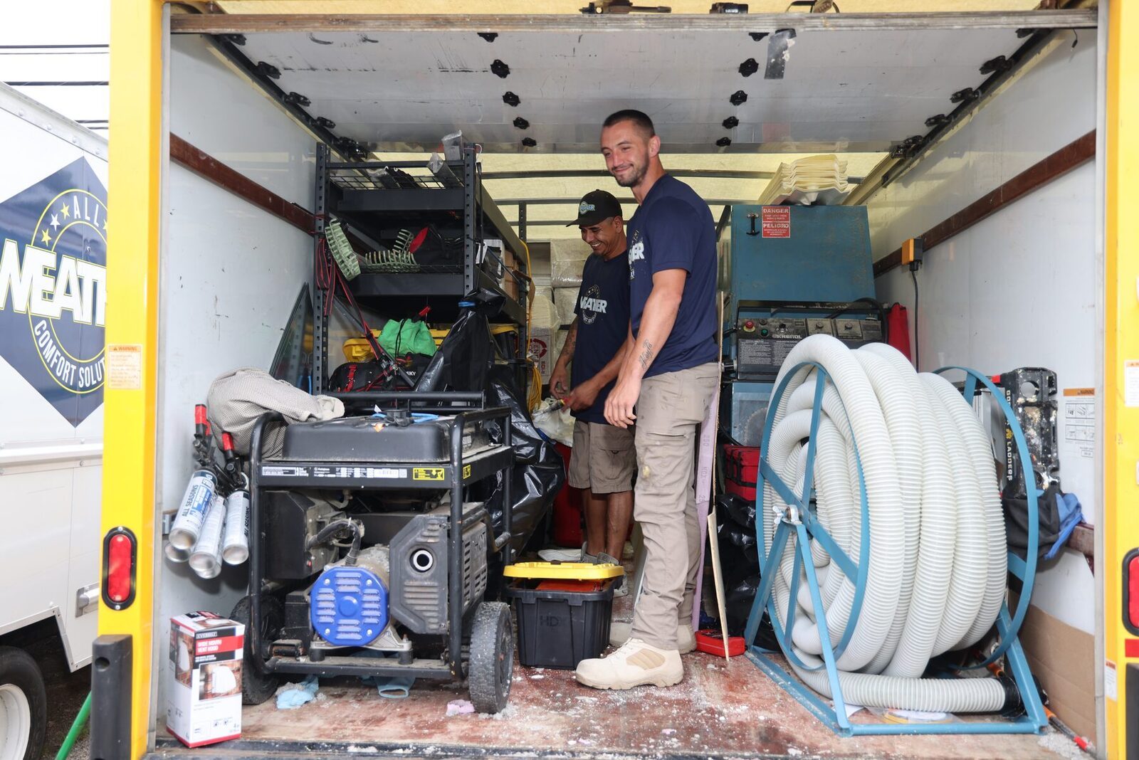 An All Weather Comfort Solutions technician organizing equipment inside a box truck